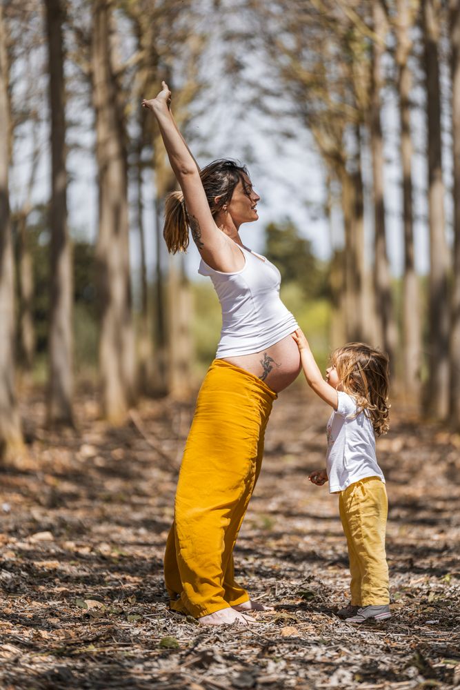 Pregnant mother and little daughter having fun in park
