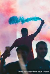 Man in red shirt holding blue smoke at a concert 4Z791b