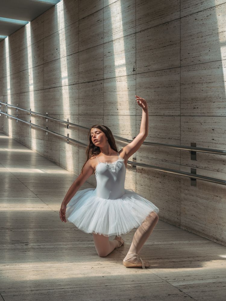 Ballerina doing ballet posing at rail in classroom