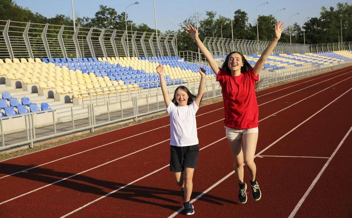 Young sisters crossing the finish line with arms raised up