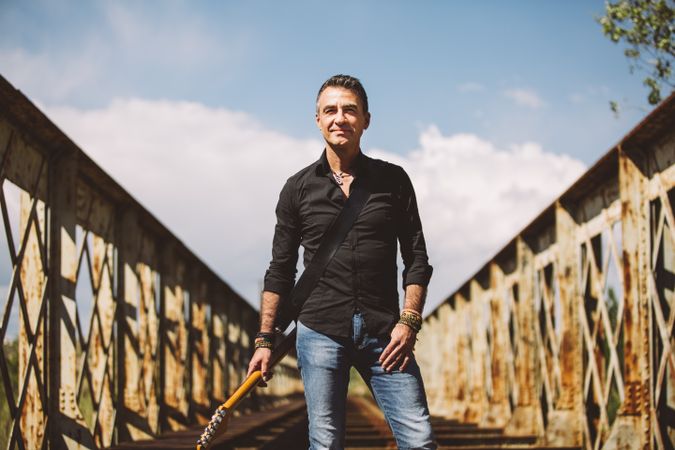 Man with guitar standing on bridge