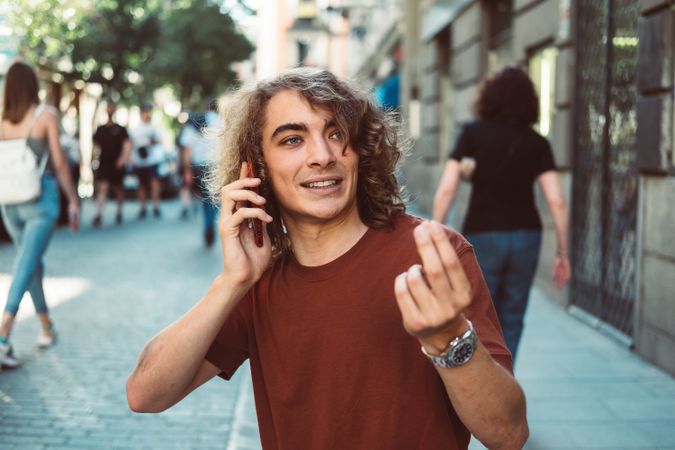 Amused man with longboard talking on phone while resting on street