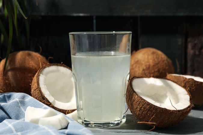 Coconut and water on wooden background, close up. Tropical fruit