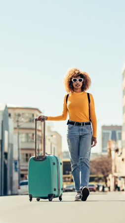 Trendy dressed woman traveling by herself and carrying travel bags