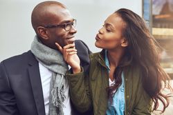 Woman being flirty holding a man’s chin in her hand