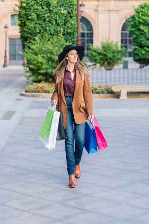 Content female in trendy wear doing shopping at city street