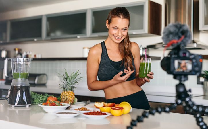 Lean woman pointing to her green juice in front of camera