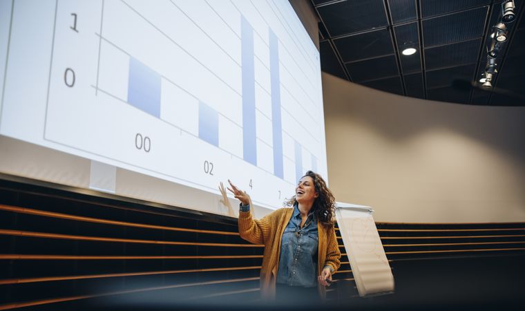 Businesswoman pointing at projection screen and delivering a presentation
