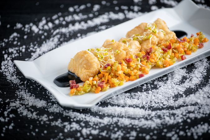 Hake breaded with matignon in rectangular plate