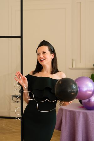 Woman holding balloons and smiling at birthday party.