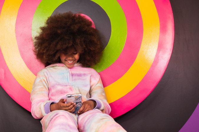 Smiling Black girl using mobile phone in studio