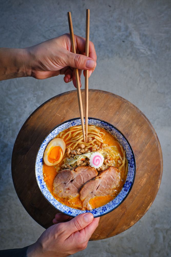 Faceless person having dinner with Asian noodle soup