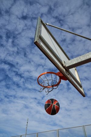 Ball falling from basketball rim on outdoor sports ground