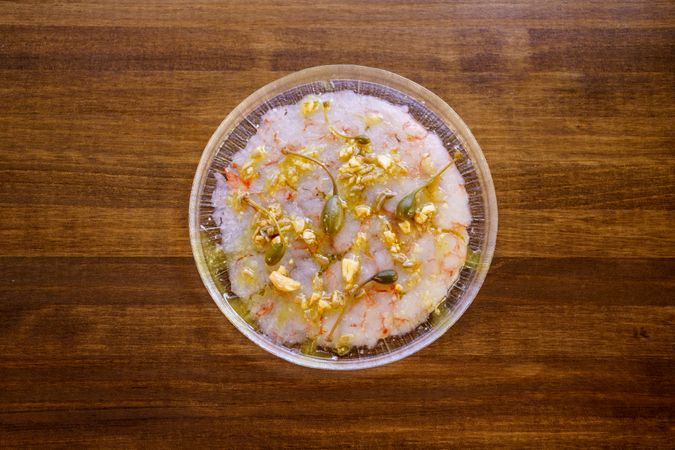 Top view of prawn carpaccio garnished with capers and nut