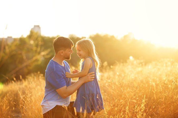 Dad and daughter resting in field of long grass