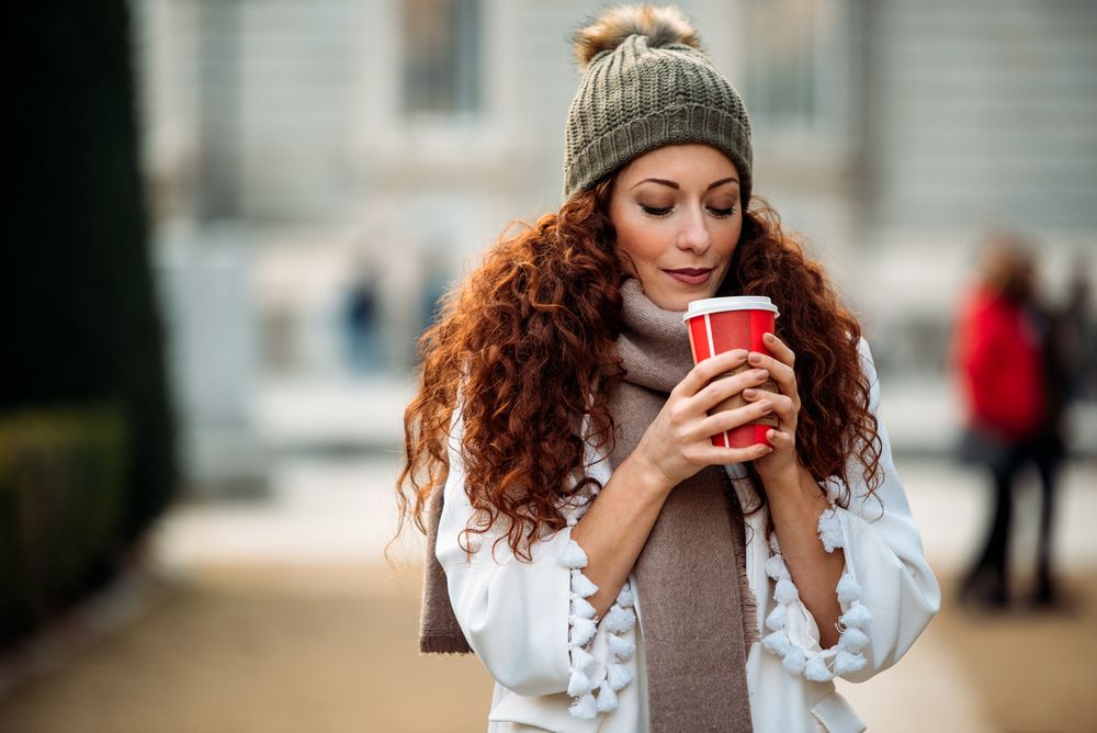 Woman drinking coffee wandering in the streets of Madrid on winter