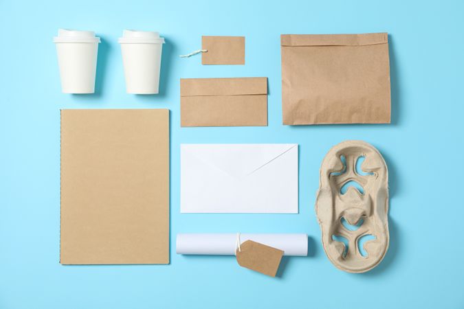 Flat lay. Paper cups and office supplies on blue background, copy space