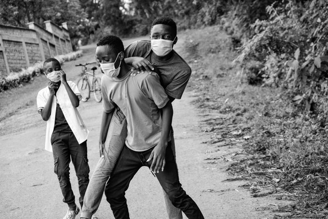 Grayscale photo of teenage boys with facemasks playing outdoor