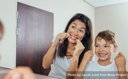 Little boy with his mother in bathroom cleaning teeth with dental floss bx3dr4