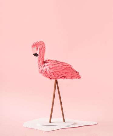 Flamingo made of paper on pink background