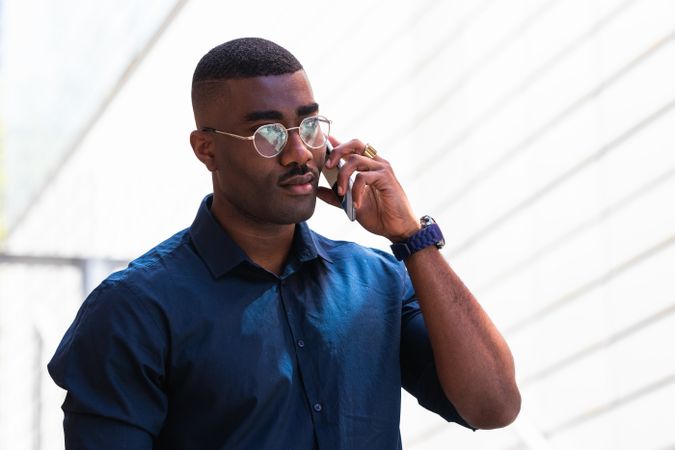 Serious Black male talking on cellphone in street