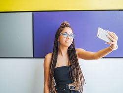 Woman with dreadlocks in glasses taking selfie
