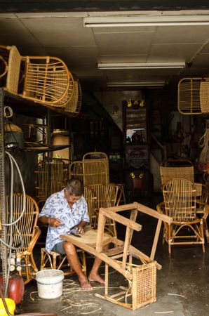 Older man making wooden chairs in a store in George Town, Penang, Malaysia