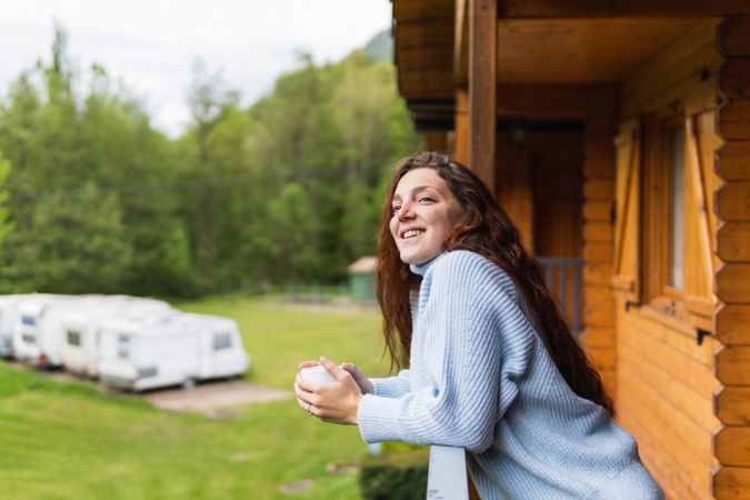Cheerful woman on terrace of house in mountains