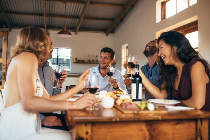 Men and women toasting red wine at dinning table during dinner party