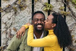cute Black couple kissing on the cheek and smiling