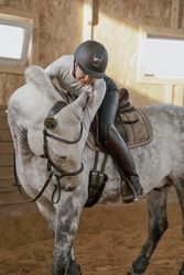 Rider riding dapple gray horse in round arena