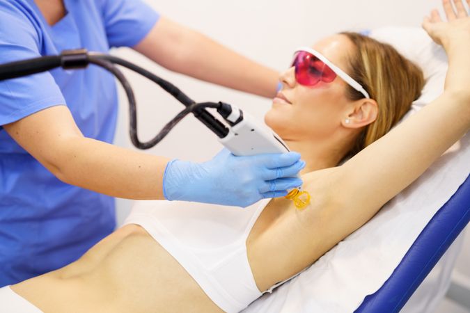 Woman receiving underarm laser hair removal at a beauty center