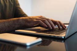 Faceless man typing on laptop