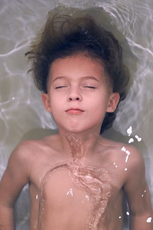 Content little kid having bath with closed eyes