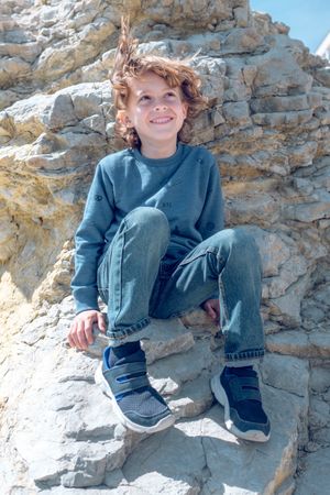 Dreamy boy on rocky cliff