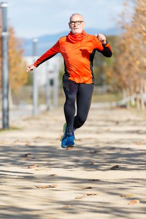 Older male leaping while working out in park