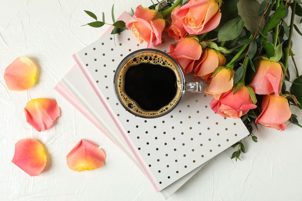 Composition with cup of coffee, notebooks and pink roses, top view