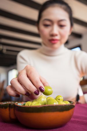Asian woman eating olives in restaurant