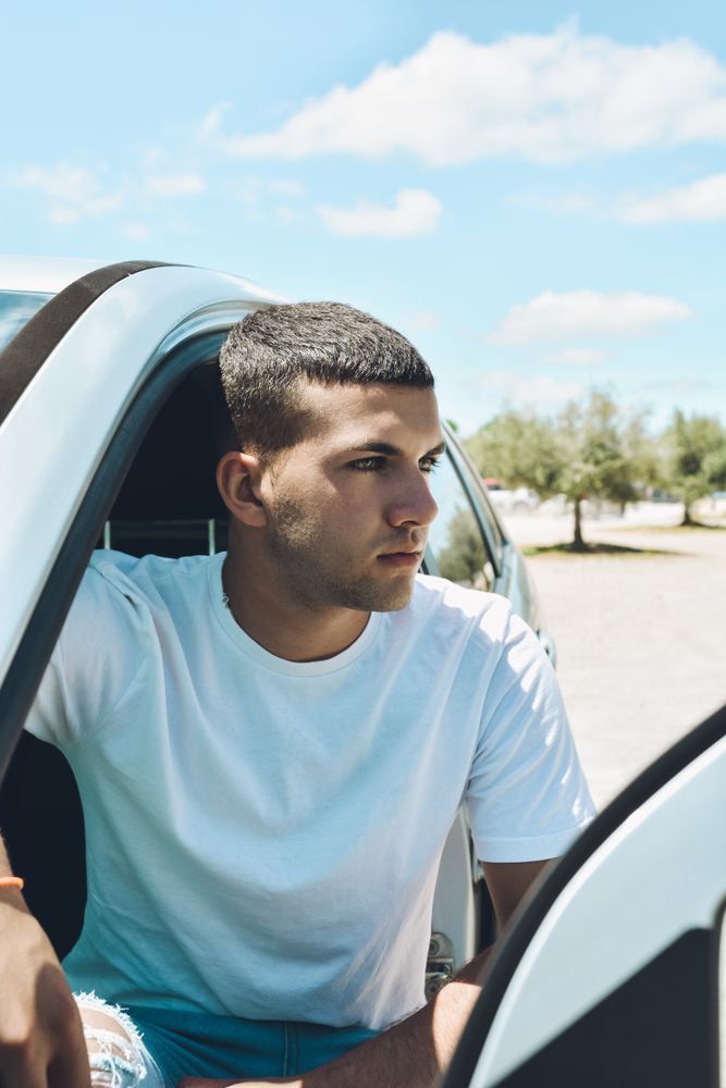 Young man and modern clothes getting off his car