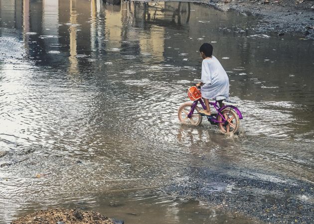 Boy riding a bike on shallow water on the road