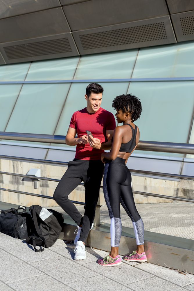 Sportsman showing app on smartphone to sportswoman