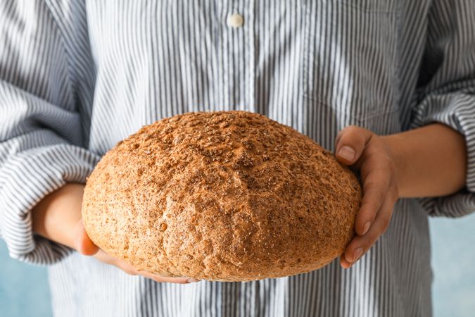 Female hands hold wheat bread against light background, space for text
