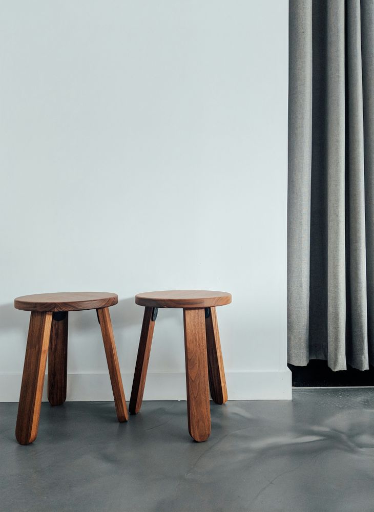 Two Wooden Stools Against White Wall Backdrop