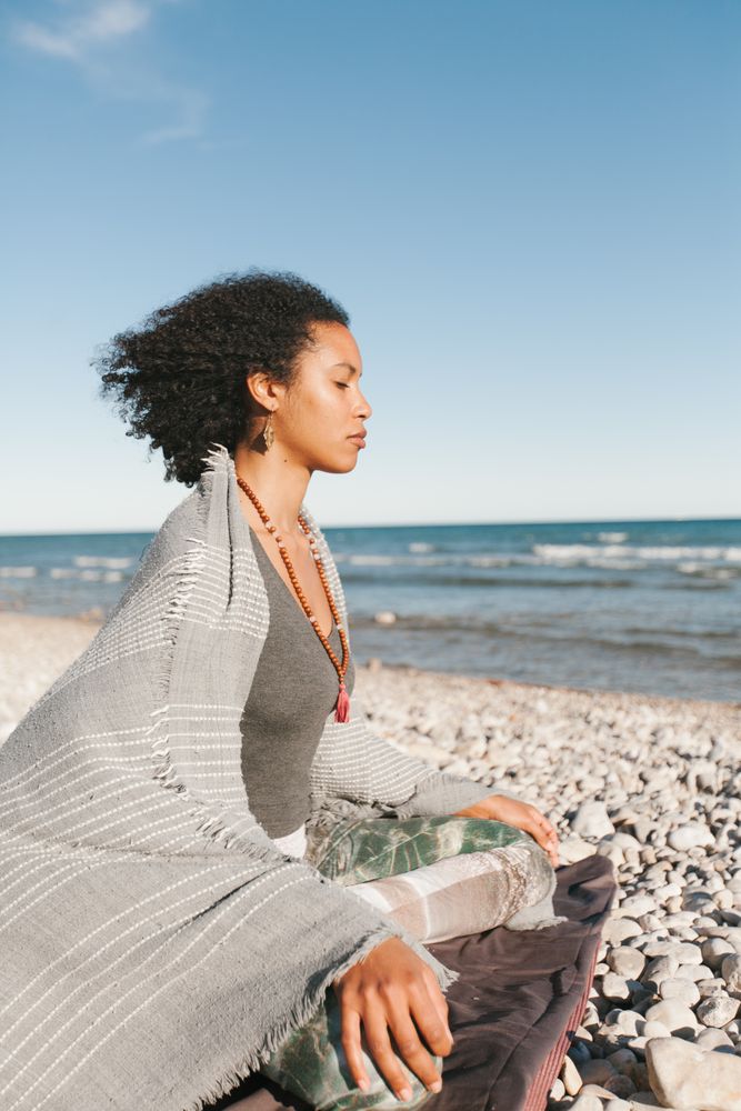 Sportive woman sitting on sandy beach in asana