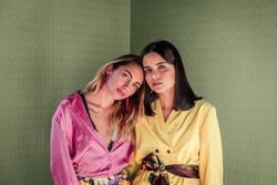 Young trendy women in bright clothes looking at camera