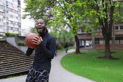 Young Black Man Enjoying Basketball Outdoors in Springtime.