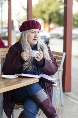 Woman holding a cup while sitting at an outdoor cafe