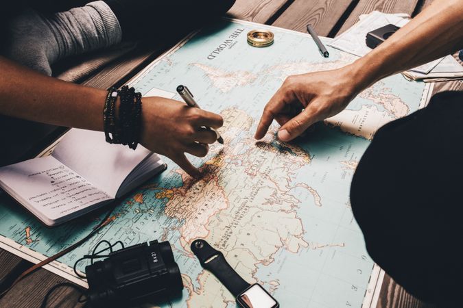 Close up view of man and woman pointing at places on world map