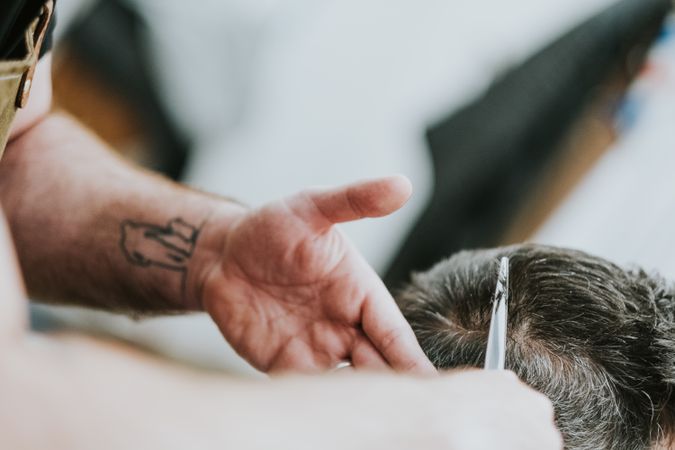 Barber cutting hair to man in salon