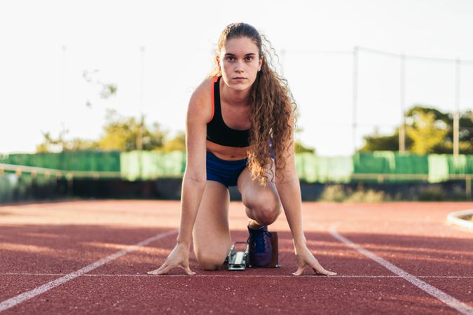 A female athlete getting ready to run on an athletics track.